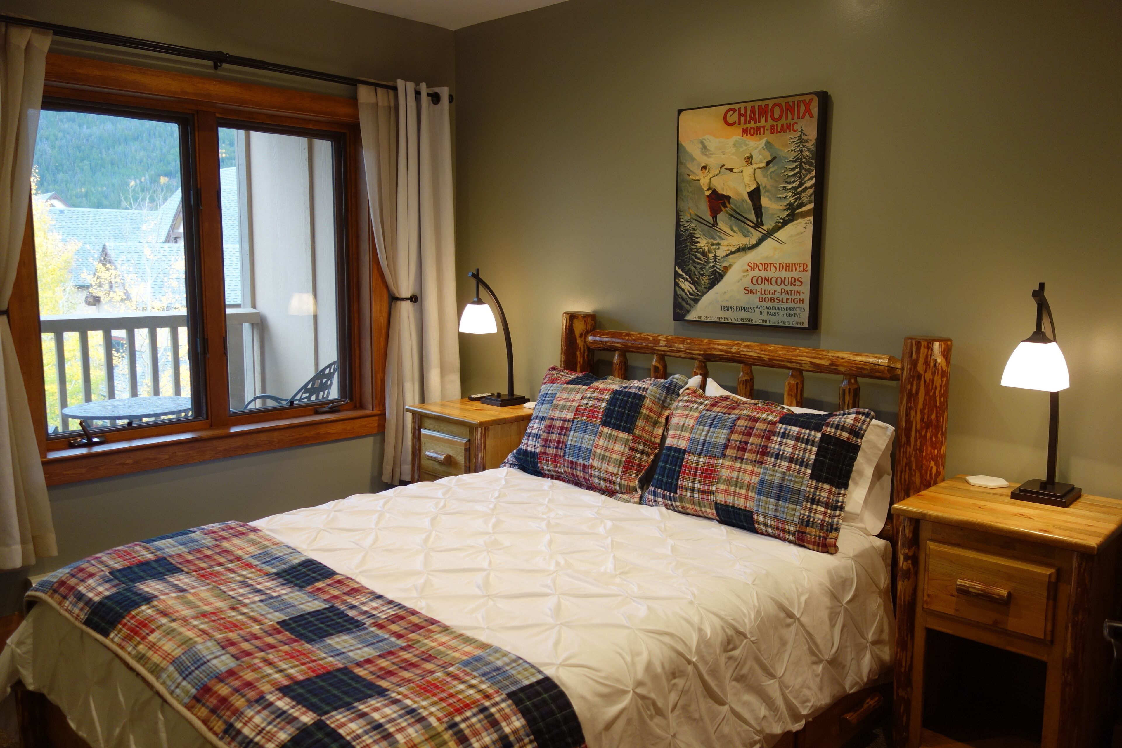 A bedroom with a bed, a nightstand, a lamp, a poster on the wall, and a window with curtains.