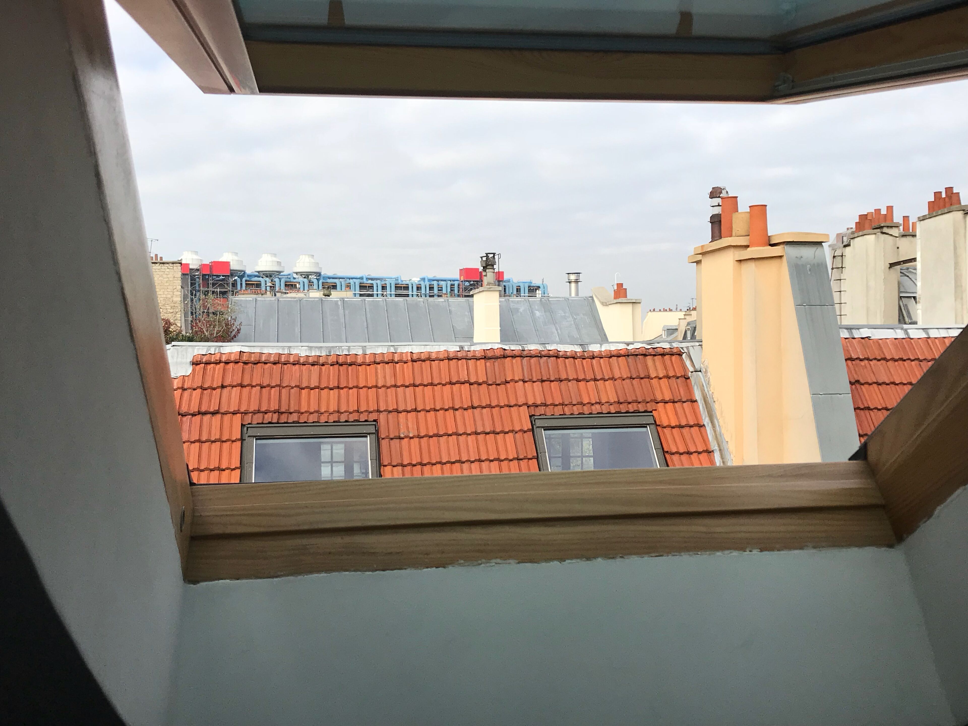 Vista desde una ventana sobre una zona residencial con tejados rojos y diversas construcciones.
