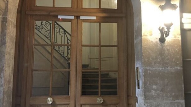 A wooden double door with glass panels and a metal staircase leading to an upper level. - Studio in Paris, Le Marais (Paris)