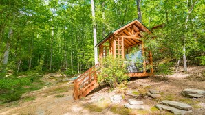 A wooden cabin with a staircase leading up to a window, surrounded by a forest. - ♨️Hot Tub🛏️King Bed🔥Fireplace 🍷Wineries🌲Oasis🥾Hike🌎Comfy🔥Fire Pit⛲Pond 🆒 (Dahlonega)