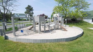 A playground with a sandpit, swings, and a slide.