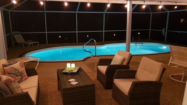 Un espace extérieur avec une piscine, des chaises longues et une table, le tout entouré d’une terrasse couverte.