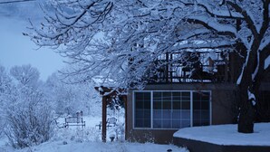 Een besneeuwde buitenruimte met een bank en een gebouw met een groot raam.