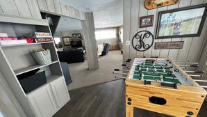 Una habitación con una mesa de fútbol de mesa, estantes con juegos de mesa y un letrero que dice 'Dream House'.
