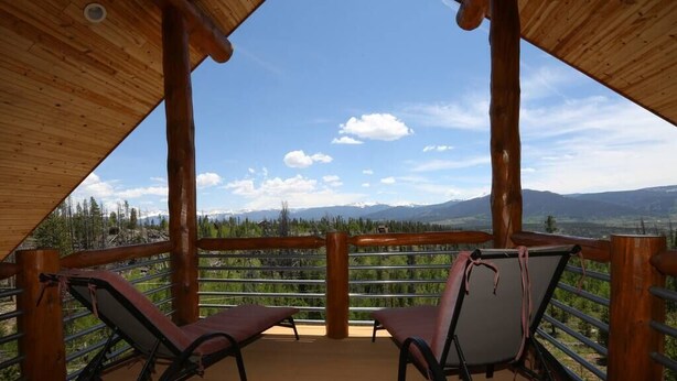 A wooden deck with two lounge chairs facing a mountainous landscape. - Secluded Log Home with Mountain View (Granby)