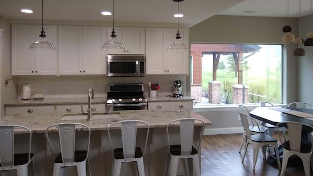 A modern kitchen with white cabinets, stainless steel appliances, and pendant lighting.