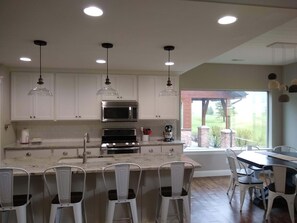 Una cocina moderna con armarios blancos, electrodomésticos de acero inoxidable e iluminación colgante.