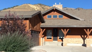 A two-story lodge with a stone facade, a large garage, and a mountain backdrop.