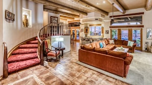 A spacious living area with a wooden staircase, a large brown sofa, and a dining area with a view. - Labor Day Available! Over the top!! Luxury, spacious, quiet family retreat. (Lake Havasu City)