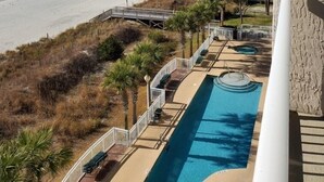 A beach view from a balcony with a swimming pool and a boardwalk leading to the beach. - Beautiful Oceanfront  Condo- Crescent Shores - Privately Owned and Maintained (North Myrtle Beach)