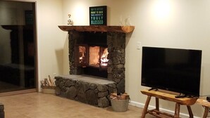 Ein Wohnzimmer mit Kamin aus Stein, einem Fernseher auf einem Holzboden und einem Schild über dem Kamin.