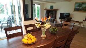Ein Essbereich mit einem Holztisch, Stühlen, einer Vase mit Blumen und einer Obstschale.