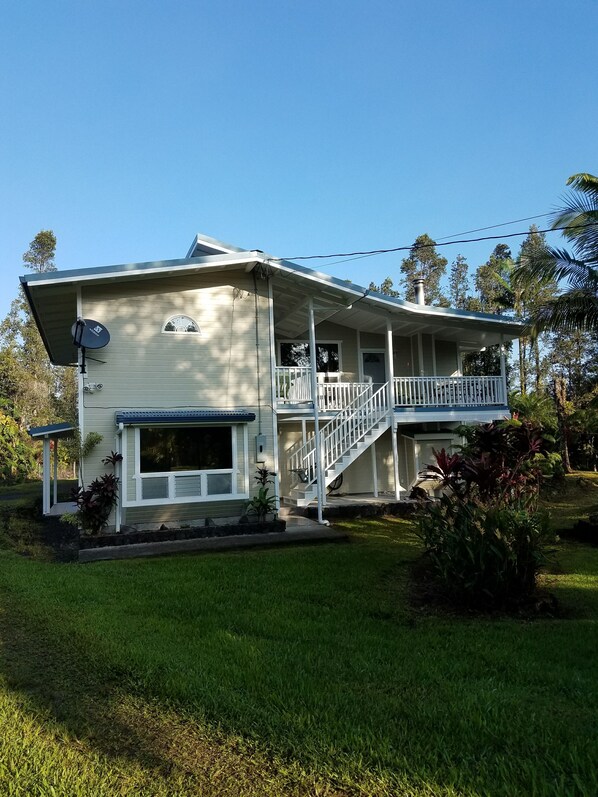 A two-story house with a covered porch, a satellite dish, and a chimney. - Spacious, 5 bd/3 ba home in Orchidland Estates (Pāhoa)