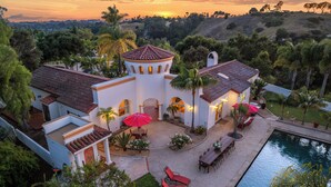 Una villa con piscina, mobiliario exterior y vistas a la puesta de sol.