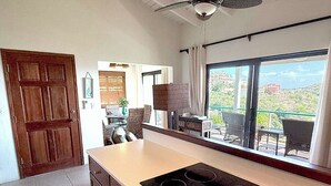 Une cuisine dotée d’un grand îlot central, de meubles en bois et offrant une vue sur l’extérieur grâce à une grande fenêtre.
