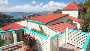 Une propriété située sur la côte, avec des toits recouverts de tuiles rouges, des murs blancs et des balustrades turquoise.