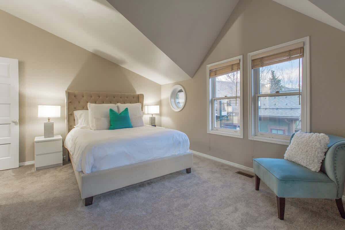 A bedroom with a bed, bedside tables, a chair, and a window.