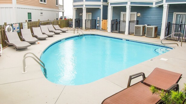 Une piscine avec des chaises longues et une terrasse en bois.