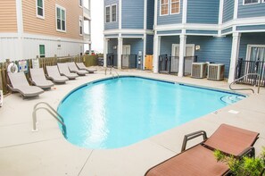 A swimming pool with lounge chairs and a wooden deck. - Pet friendly with pool (Kure Beach)