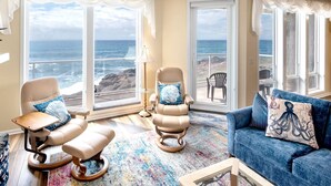 Ein Zimmer mit Meerblick, ausgestattet mit einem blauen Sofa, zwei Sesseln und einem gemusterten Teppich.
