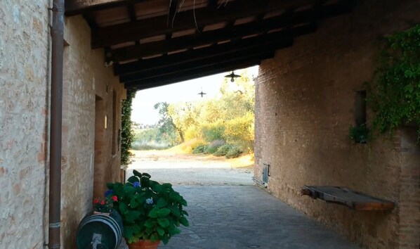 A stone pathway leading to a covered area with a rustic brick wall and a potted plant. - Belvedere Siena Hills: Tuscan farmhouse with panoramic views & A/C (Siena)