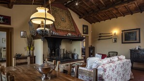 A rustic interior with a wooden dining table, a sofa with floral upholstery, and a traditional fireplace. - Traditional Tuscan farmhouse with stunning views & air conditioning (Siena)