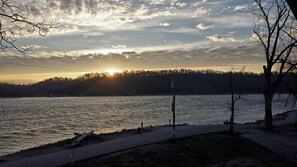 A riverside view with a sunset, a path, and trees.