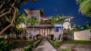 A two-story building with a central entrance, surrounded by tropical plants and a clear night sky. - Luxurious Troncones Beachfront! 30mins to Ixtapa (Troncones)