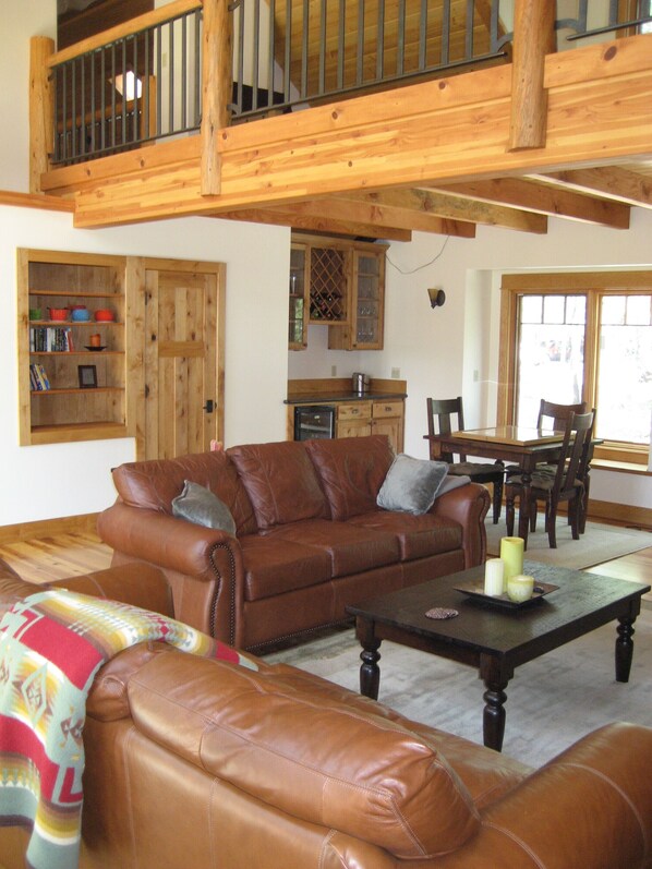 A spacious living room with a brown leather sofa, a coffee table, and a dining area with wooden furniture. - Golf Course/Lodge Style/large/clean/comfortable/5 BR (Black Butte Ranch)