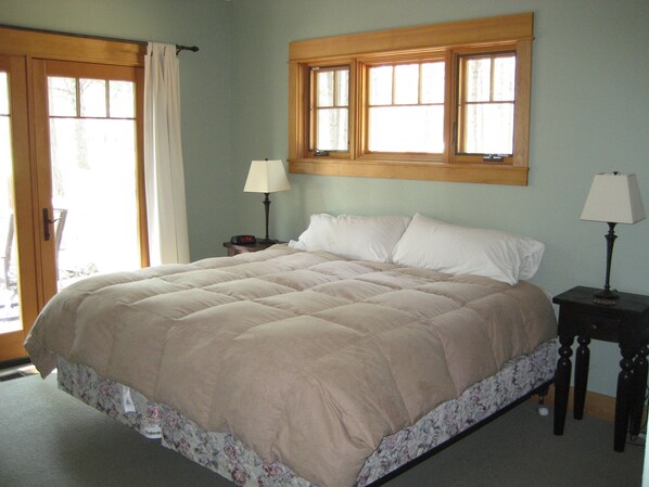 A bedroom with a large bed, two bedside tables, a window, and a door. - Golf Course/Lodge Style/large/clean/comfortable/5 BR (Black Butte Ranch)