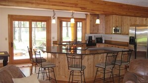 A wooden cabin interior with a kitchen island, bar stools, and a dining area. - Golf Course/Lodge Style/large/clean/comfortable/5 BR (Black Butte Ranch)