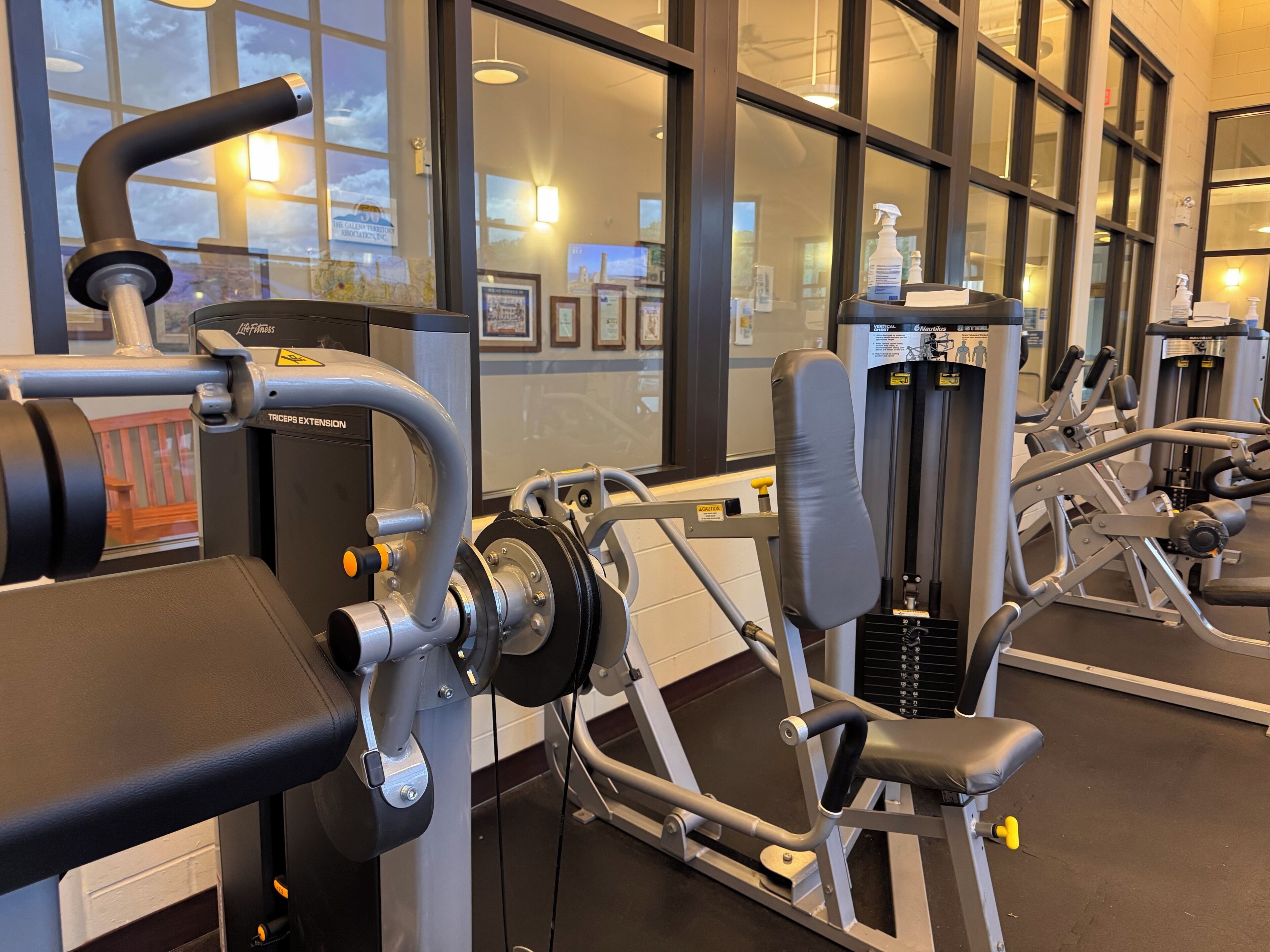 A gym with exercise equipment, large windows, and a view of the sky.