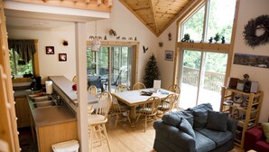 Een gezellig interieur van een chalet, met een eethoek, een woonkamer met een bank en een keuken.