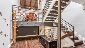 A loft bedroom with a wooden tree, a trunk-shaped bench, a suitcase, and a staircase. - Spacious Beach House (Solana Beach)