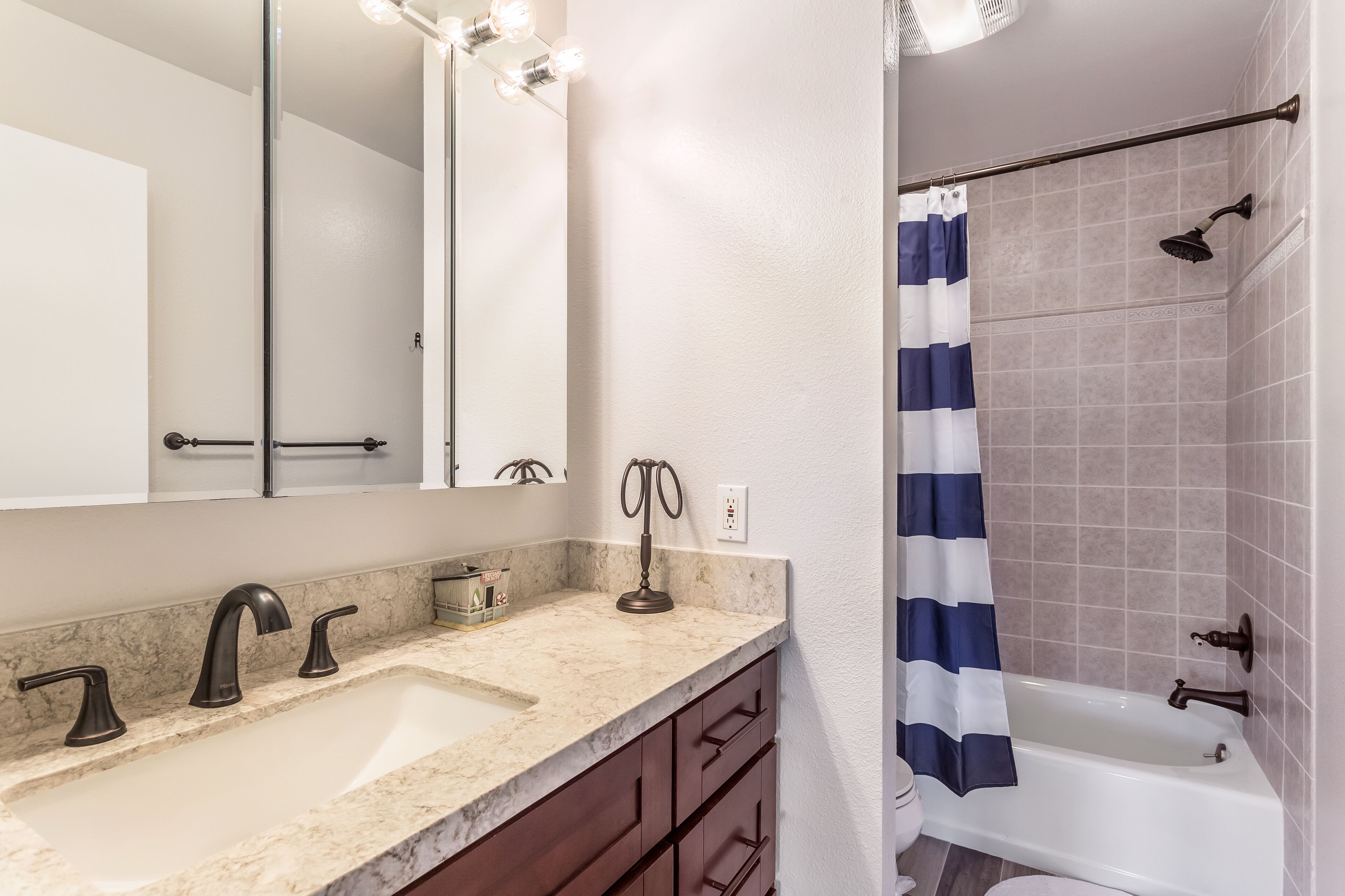 A bathroom with a sink, mirror, vanity, and shower area.
