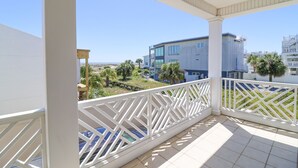 Een balkon met overkapping, uitzicht op een modern gebouw en palmbomen.