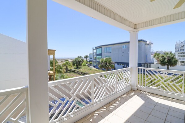 A covered balcony with a view of a modern building and palm trees.