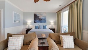 Een hotelkamer met een groot bed, twee banken, een kleine tafel en een schilderij aan de muur.