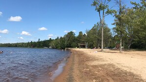 A beach with a sandy shore, trees, and a lake. - 4 Season Cottage at Lake Vernon - Perfect for families! (Huntsville)