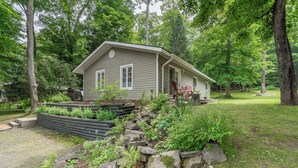 A cabin with a porch, surrounded by a garden and trees. - 4 Season Cottage at Lake Vernon - Perfect for families! (Huntsville)
