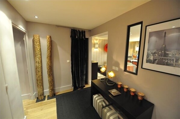 A modern hotel room with a wooden floor, a black console table with decorative lights, a mirror, and a framed picture of a cityscape. - Perfect Location to Visit All of Paris - Contemporary Cozy (Paris)