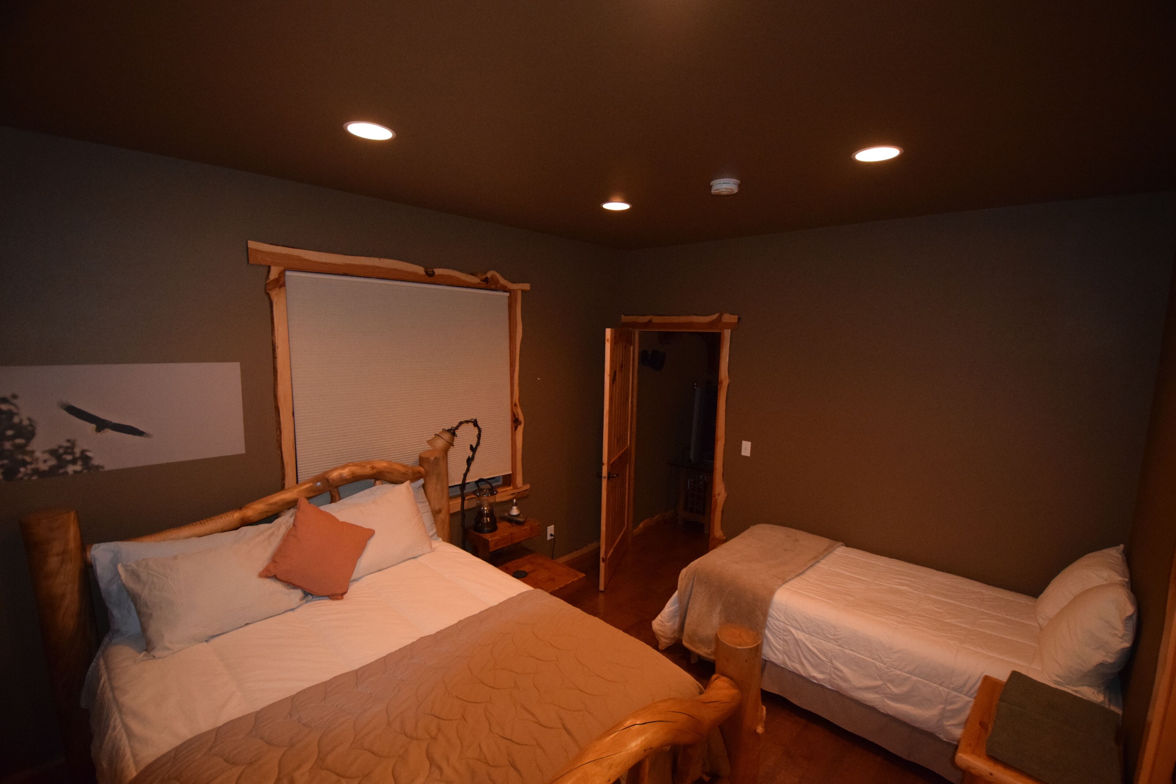 A bedroom with two beds, wooden headboards, and a large window.