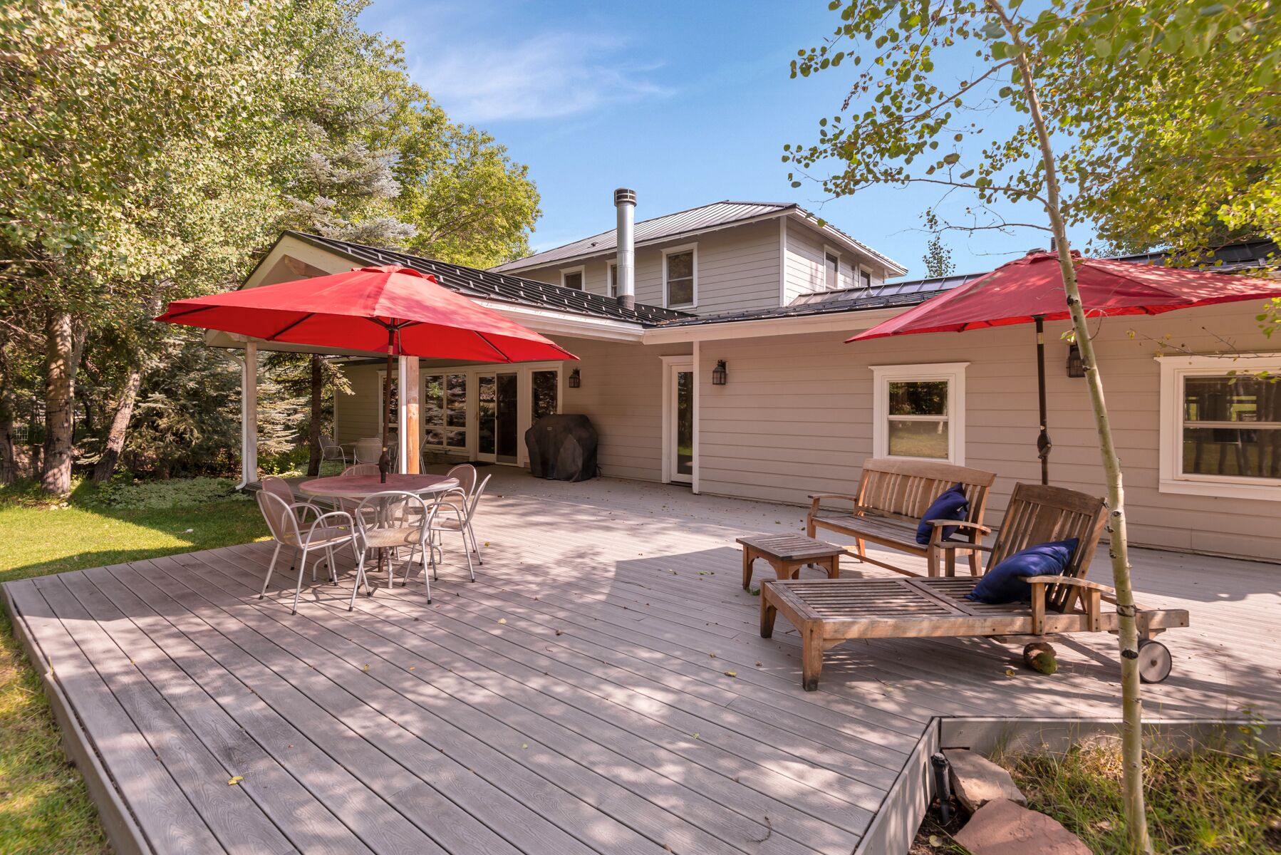 Un patio techado con mesa y sillas, una parrilla y una terraza de madera.