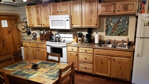 A kitchen with wooden cabinets, a white stove, a microwave, and a sink.