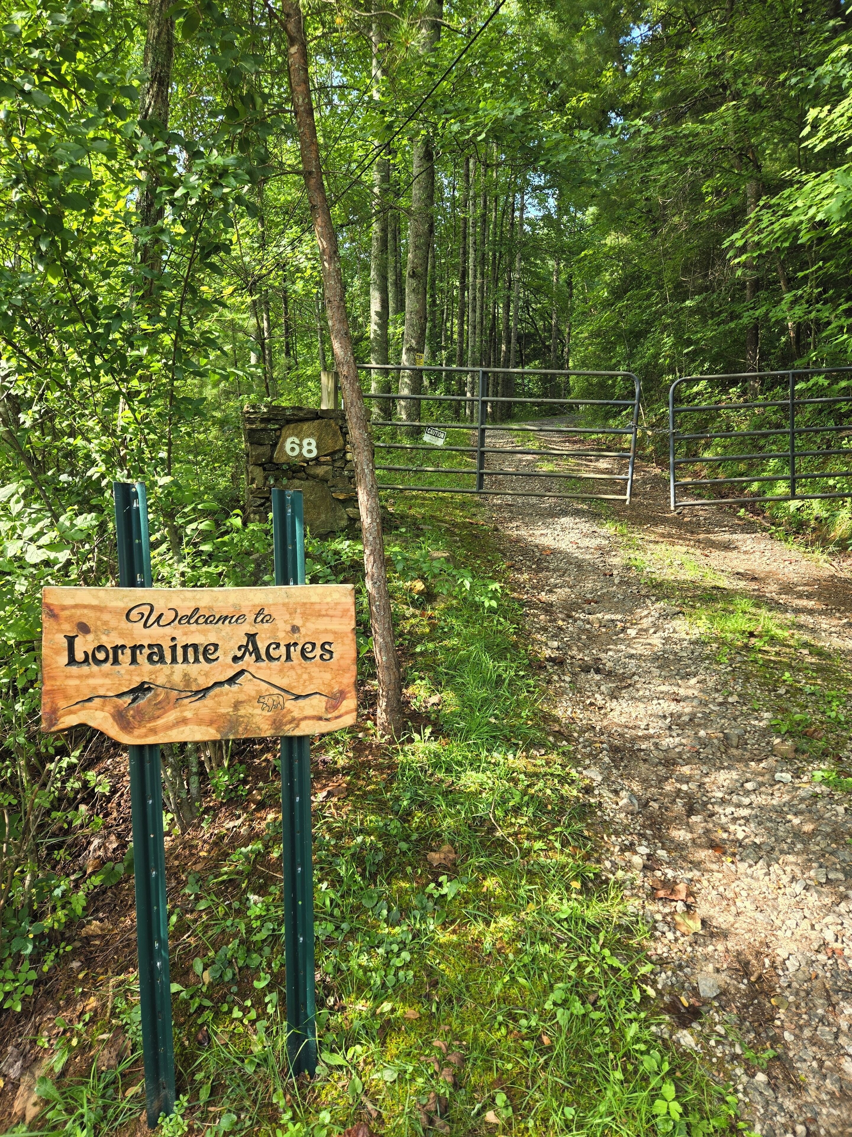 A wooden welcome sign for Lorraine Acres with a stone number 68 sign in the background.
