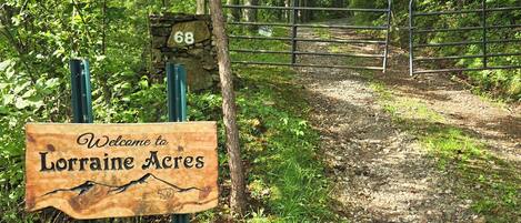 A wooden welcome sign for Lorraine Acres with a stone number 68 sign in the background.