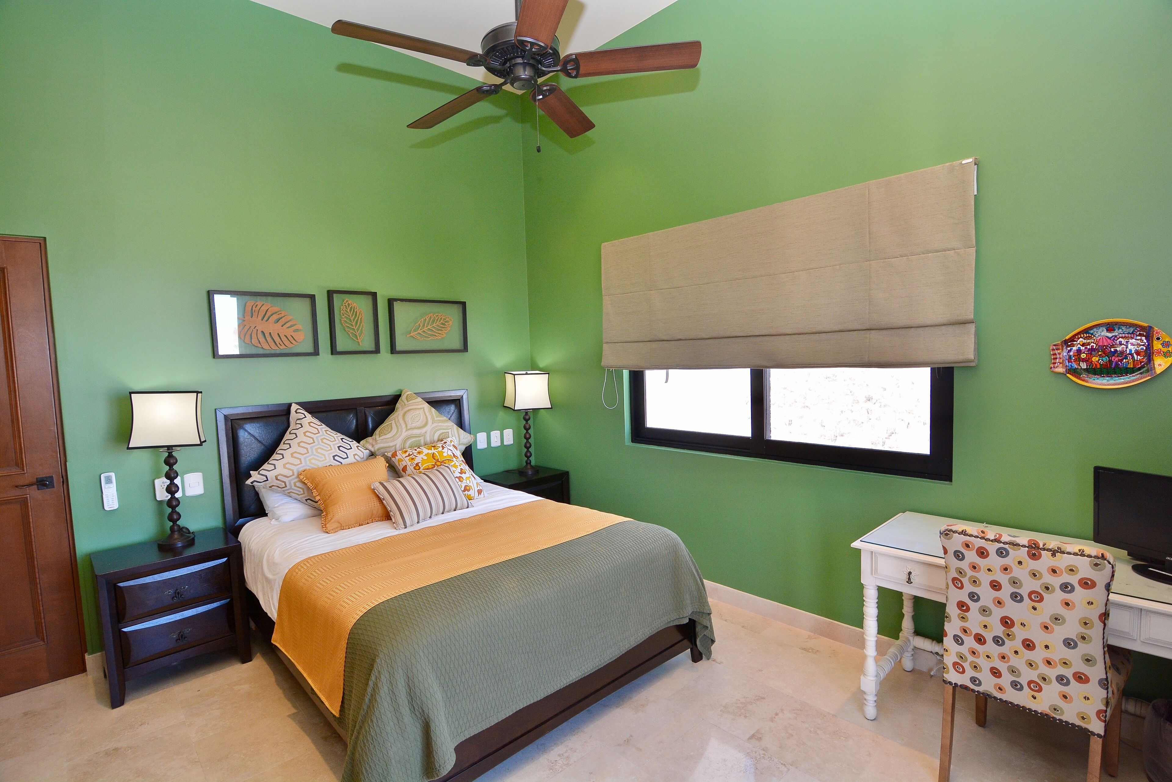 A bedroom with a bed, bedside tables, a desk, and a chair.