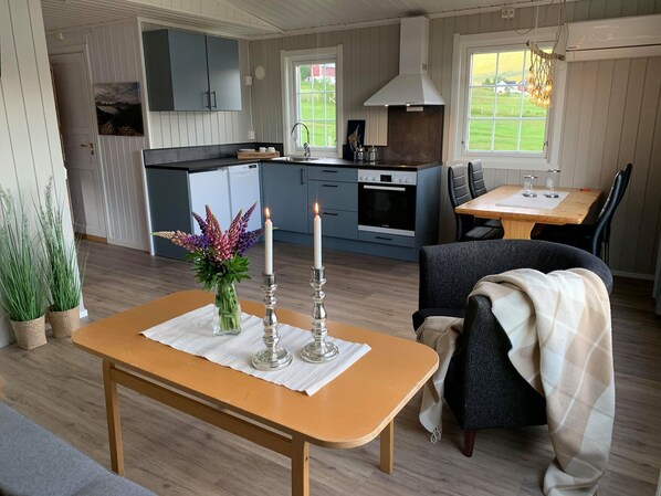 A modern kitchen with a built-in oven and a dining area with a table and chairs. - Aa Gård (Lavangen)