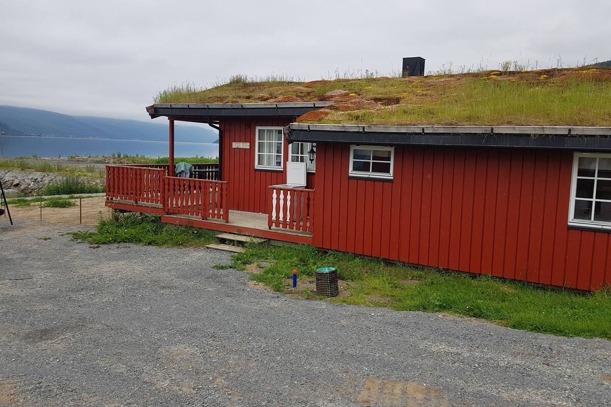 A red cabin with a balcony, a small porch, and a view of the sea.