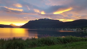 A serene lakeside view with mountains in the background and a clear sky. - Aa Gård (Lavangen)